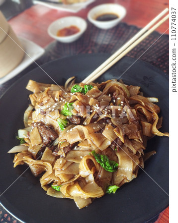 Pad see ew or thai stir-fried noodles served in a black plate  Pad see ew or thai stir-fried noodles served in a black plate  110774037