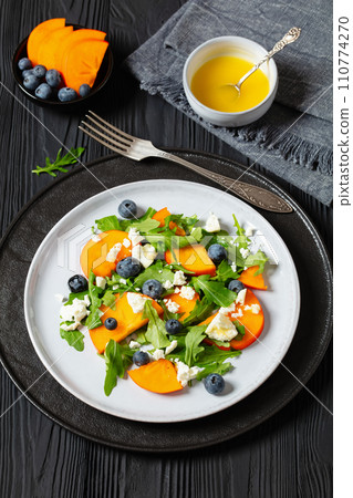 arugula persimmon cheese berries salad, top view arugula persimmon cheese berries salad, top view 110774270