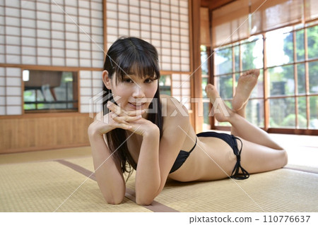 一個穿著黑色比基尼泳裝的年輕女子在老民居的日式房間裡放鬆 110776637