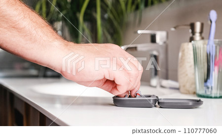 Adult man taking hearing aids from the bathroom Adult man taking hearing aids from the bathroom 110777060