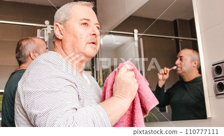 Gay couple brushing their teeth and cleaning the face in the bathroom after waking up 110777111
