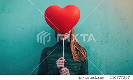 A red heart shaped balloon in the womans hands 110777237