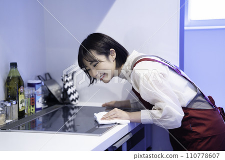 一個穿著圍裙的女人正在擦拭廚房 110778607