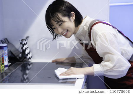A woman in an apron wiping down the kitchen A woman in an apron wiping down the kitchen 110778608