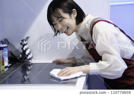 一個穿著圍裙的女人正在擦拭廚房 110778609