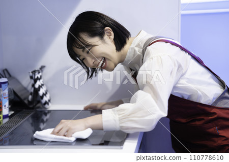 一個穿著圍裙的女人正在擦拭廚房 110778610