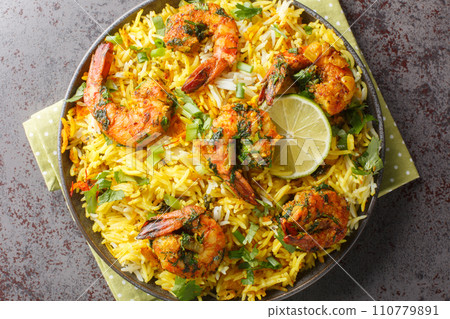 Asian saffron pilaf with shrimp and lots of herbs such as dill, green onions, cilantro close-up on a plate. Horizontal top view 110779891