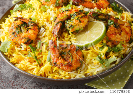 Asian saffron pilaf with shrimp and lots of herbs such as dill, green onions, cilantro close-up on a plate. Horizontal 110779898