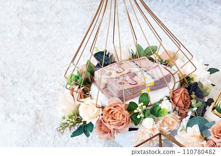 Close up of piles of Khan Mak money in a basket for thai wedding traditions. Close up of piles of Khan Mak money in a basket for thai wedding traditions. 110780482