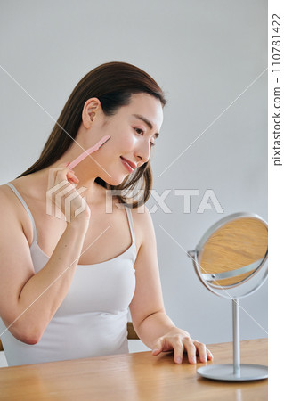 A woman in her 30s shaving her face with a ladies razor 110781422