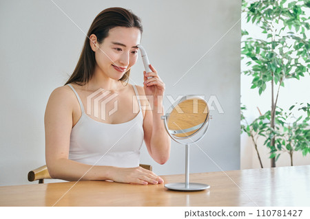 A woman in her 30s shaving her face with an electric shaver A woman in her 30s shaving her face with an electric shaver 110781427