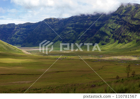 Landscape of green hills in the mountains on a cloudy day. Location of Mount Bromo in Bromo Tengger Semeru National Park, East Java, Indonesia 110781567