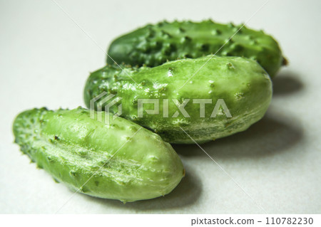 Green cucumbers on a light background Green cucumbers on a light background 110782230