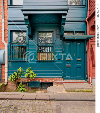 Green house with wooden decorated door and ornate wrought iron windows, Kuzguncuk Istanbul, Turkey 110782592