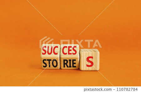 Success stories symbol. Turned wooden cubes and changed the word stories to success. Beautiful orange table, orange background, copy space. Business success stories story concept. Success stories symbol. Turned wooden cubes and changed the word stories to success. Beautiful orange table, orange background, copy space. Business success stories story concept. 110782784