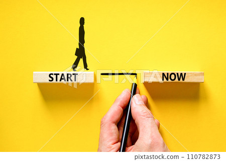 Start now symbol. Concept words Start now on beautiful wooden block. Beautiful yellow table yellow background. Businessman hand. Business marketing, motivational start now concept. Copy space. 110782873