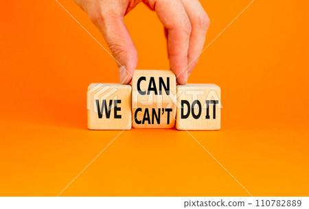 We can do it symbol. Concept word We can or can not do it on beautiful wooden cubes. Beautiful orange table orange background. Businessman hand. Business and we can or not do it concept. Copy space. 110782889