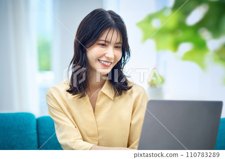 Woman operating a computer at home Woman operating a computer at home 110783289