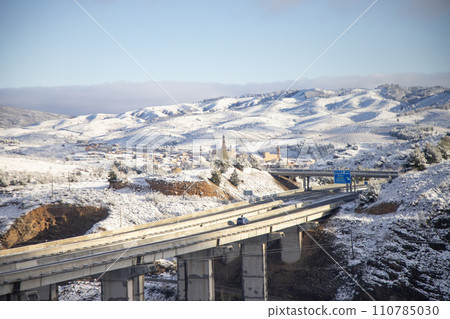 Snow. Winter landscape covered in a white blanket of snow covering mountains and roads. Trees with snow. Clear day. White blanket due to a storm with heavy snowfall. In Spain. January. 2024. Snow. Winter landscape covered in a white blanket of snow covering mountains and roads. Trees with snow. Clear day. White blanket due to a storm with heavy snowfall. In Spain. January. 2024. 110785030