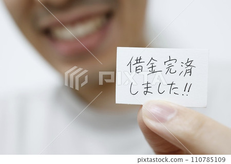 一名男子拿著一張紙,上面寫著“我還清了債務” 一名男子拿著一張紙,上面寫著“我還清了債務” 110785109