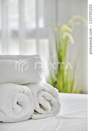 Three folded white towels on bed in cozy bedroom Three folded white towels on bed in cozy bedroom 110785203