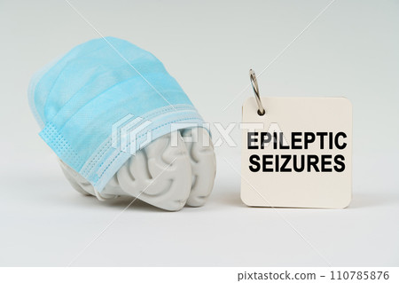 On a white surface next to the brain there is a notepad with the inscription - epileptic seizures 110785876