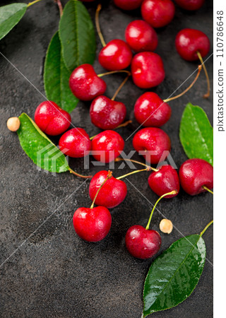 Ripe sweet cherry berry with leaves on a black wooden board. Ripe sweet cherry berry with leaves on a black wooden board. 110786648