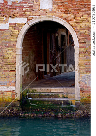 Italy. Close-ups of building facades in Venice. A look at the old scratched arch in the wall near the water in the canal. 110786662