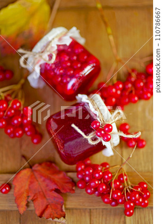 viburnum jam. Red juicy berries of a viburnum with sugar in a glass jar on a dark wooden background. For making jam, tea. Medicinal plant. viburnum jam. Red juicy berries of a viburnum with sugar in a glass jar on a dark wooden background. For making jam, tea. Medicinal plant. 110786667