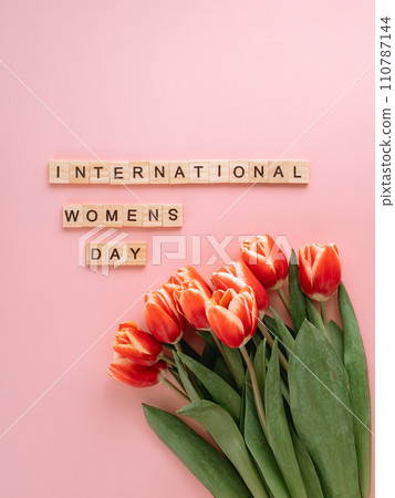 International women's day or eight march concept with copy space. International women's day text and bunch of red tulip on pink background. Top view or flat lay. Vertical International women's day or eight march concept with copy space. International women's day text and bunch of red tulip on pink background. Top view or flat lay. Vertical 110787144