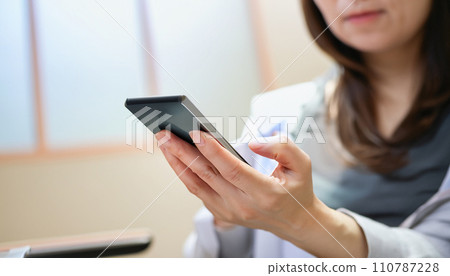 The hands of a middle-aged woman operating a smartphone The hands of a middle-aged woman operating a smartphone 110787228
