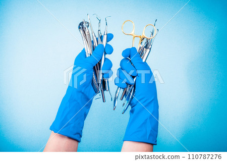 Hands in blue gloves holding surgery dental equipment Hands in blue gloves holding surgery dental equipment 110787276