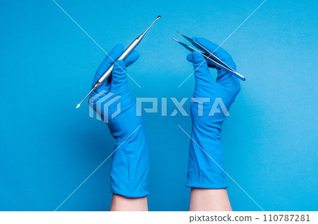 Hands in blue gloves holding dental surgery sticks 110787281