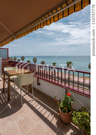 Shady terrace with table and potted plants by sea beach 110787776