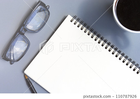 Notepad with coffee cup, reading glasses and a pen on a desk. Copy space. 110787926