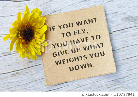 Motivational quote on torn brown paper on wooden surface with sunflowers. Motivational quote on torn brown paper on wooden surface with sunflowers. 110787941