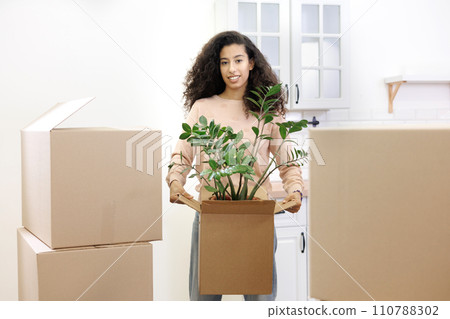 happy young African American woman is moving into new home. person stands among cardboard boxes happy young African American woman is moving into new home. person stands among cardboard boxes 110788302