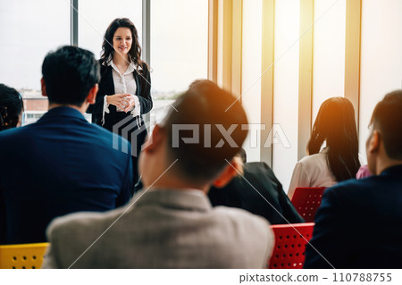 Office meeting with a diverse group of businesspeople. Seated colleagues converse, while male and female managers stand, facilitating a dynamic exchange of ideas. Office meeting with a diverse group of businesspeople. Seated colleagues converse, while male and female managers stand, facilitating a dynamic exchange of ideas. 110788755