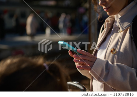 Close-up woman checking her online ticket on mobile app on her smartphone, waiting for the train in the railway station 110788916
