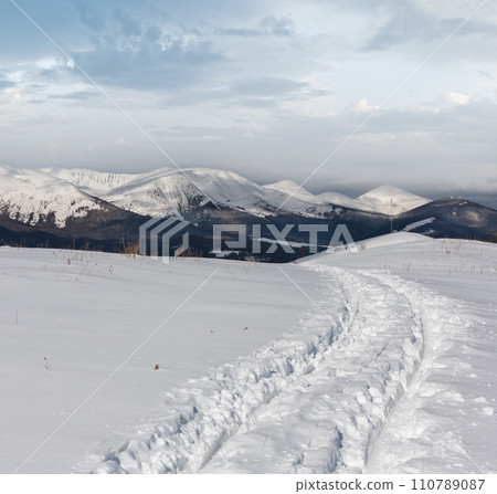 Sledge trace and footprints on winter mountain hill top 110789087