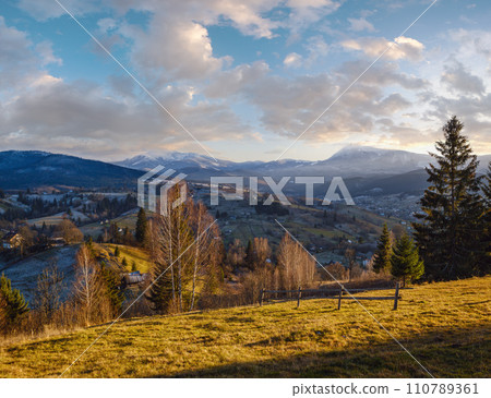 Late autumn mountain pre sunset scene with snow covered tops in far. Picturesque traveling, seasonal, nature and countryside beauty concept scene. Carpathians, Ukraine. 110789361