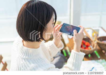 一個正在拍照的女人 一個正在摘草莓的女人 一個正在摘草莓的女人 110789897