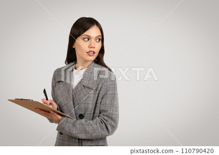 Thoughtful woman with clipboard on grey background, free space Thoughtful woman with clipboard on grey background, free space 110790420