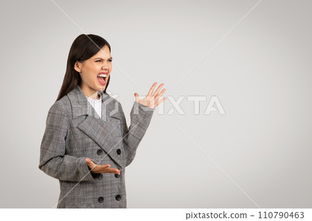 Angry woman in gray blazer shouting with hand gesture 110790463