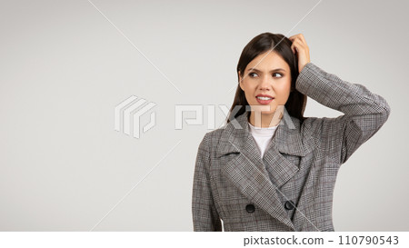 Puzzled woman in houndstooth jacket scratching head, looking away at free space Puzzled woman in houndstooth jacket scratching head, looking away at free space 110790543