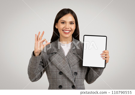 Happy woman holding tablet with blank screen showing okay sign 110790555