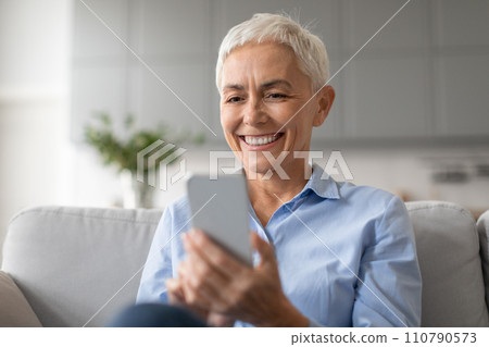 Portrait of happy mature lady surfing internet communicating on cellphone 110790573
