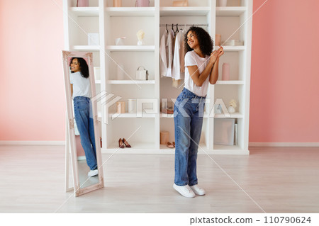 Woman in jeans smiling at her reflection 110790624