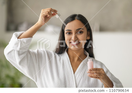 Attractive young indian woman applying moisturizing serum onto her face 110790634