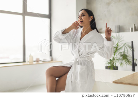 Happy young eastern woman listening to music in bathroom 110790657